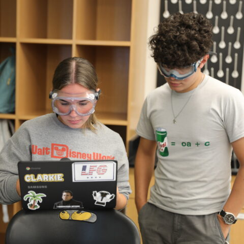 A male and female students typing results into a computer.