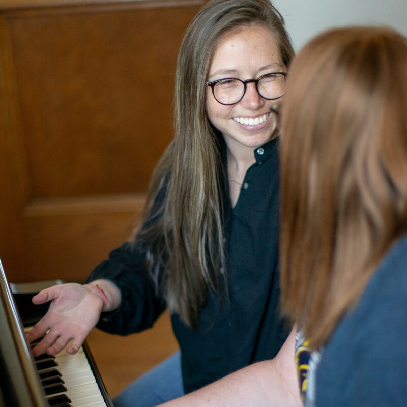 A female professor instructing a student at a piano.