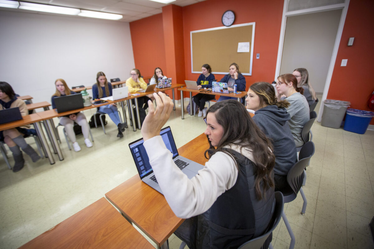 A student raising their hand in a classroom. - Full Size