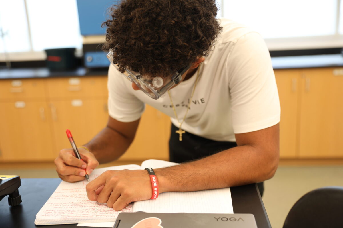 A male college student taking notes of an experiment. - Full Size