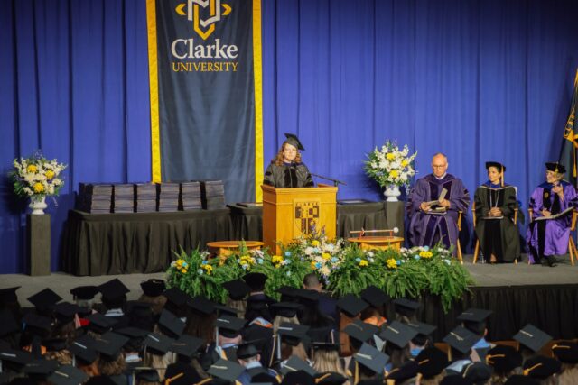 A woman reads from a podium at Clarke's Commencement Celebration.