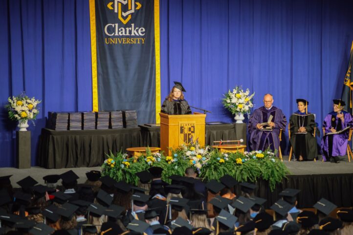 A woman reads from a podium at Clarke's Commencement Celebration.
