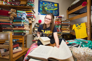 Abby Funke posing with a lot of reading materials